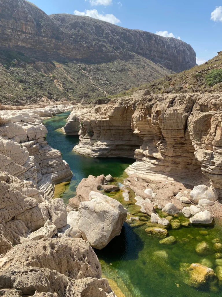 Rocky canyon with turquoise river in a mountainous desert landscape under a blue sky